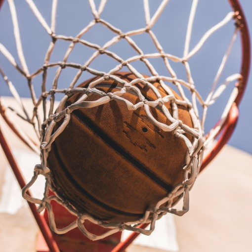 Close-up van een basketbal die door de basket valt, uiteraard voorzien van een NK Basketbalnet